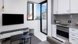 Une cuisine moderne avec des armoires blanches, un four encastré et une grande fenêtre donnant sur la ville.