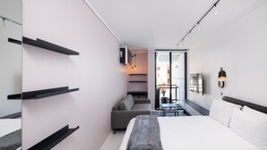 Une chambre d’hôtel moderne équipée d’un lit, d’un canapé, d’une petite table et d’étagères intégrées.