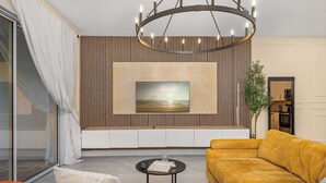 Ein modernes Wohnzimmer mit großem Fenster, einer Couch, einem Couchtisch und einem Gemälde an der Wand.