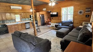 A spacious living area with a large gray sofa, a wooden coffee table, and a TV mounted on the wall.
