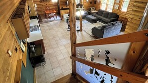 A wooden cabin interior with a dining area, kitchen, and living room.