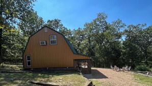 A wooden barn with a covered porch and a gravel driveway.