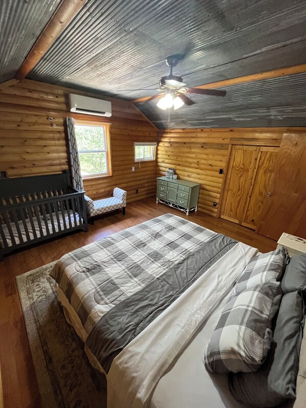 Un dormitorio tipo cabaña de madera con una cama, cómoda y cuna.