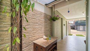 A hallway with a stone wall, a wooden bench, and hanging plants. - 918 - Casa grande 3 Quartos 8 pessoas (Bombinhas)