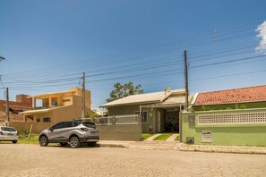 Une rue résidentielle bordée de maisons, avec une voiture garée et des lignes électriques aériennes.