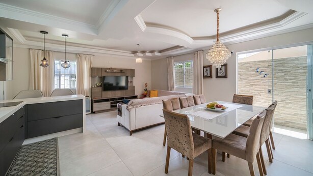 A spacious living area with a dining table, sofas, and a TV. - 918 - Casa grande 3 Quartos 8 pessoas (Bombinhas)