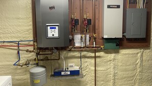 A water heater, a control panel, and a boiler in a utility room with visible pipes and a pressure gauge. - Riverview home (Pittsburg)