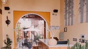 A lobby with a central reception desk, potted cacti, a chandelier, and a view of the interior through an archway. - Mestizo Antigua (Antigua Guatemala)