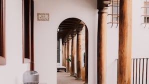 A corridor with columns, a woven basket, and a sign. - Mestizo Antigua (Antigua Guatemala)