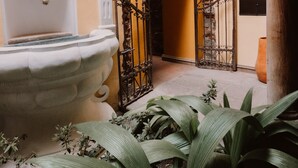 A courtyard with a fountain, an archway, and a gate. - Mestizo Antigua (Antigua Guatemala)