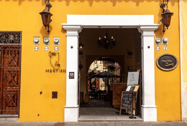 A yellow building with a sign reading "MESTIZO" and a signboard for "Bistro Bar Bar Restaurante". - Mestizo Antigua (Antigua Guatemala)