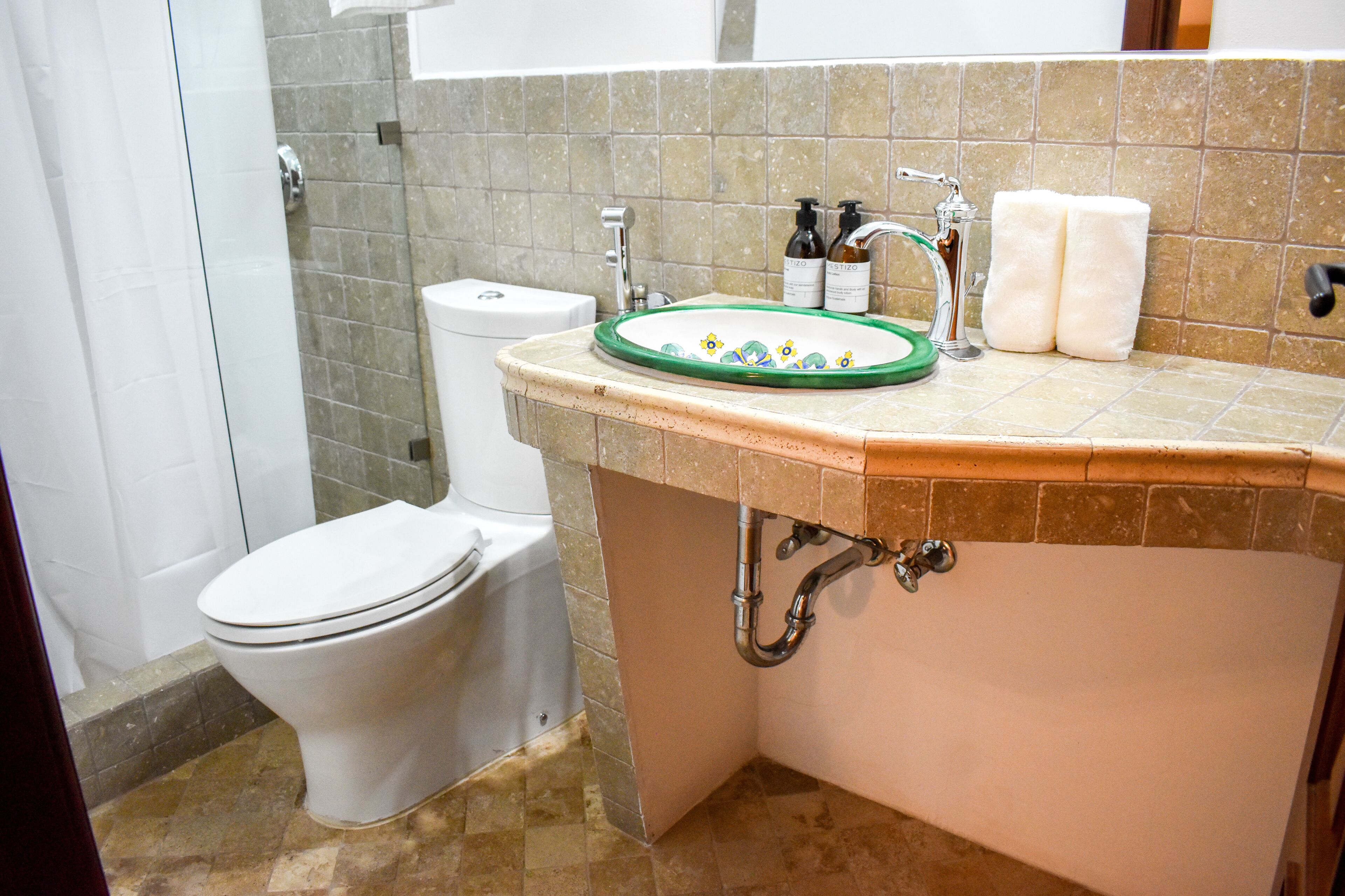 A bathroom with a toilet, sink, and shower.