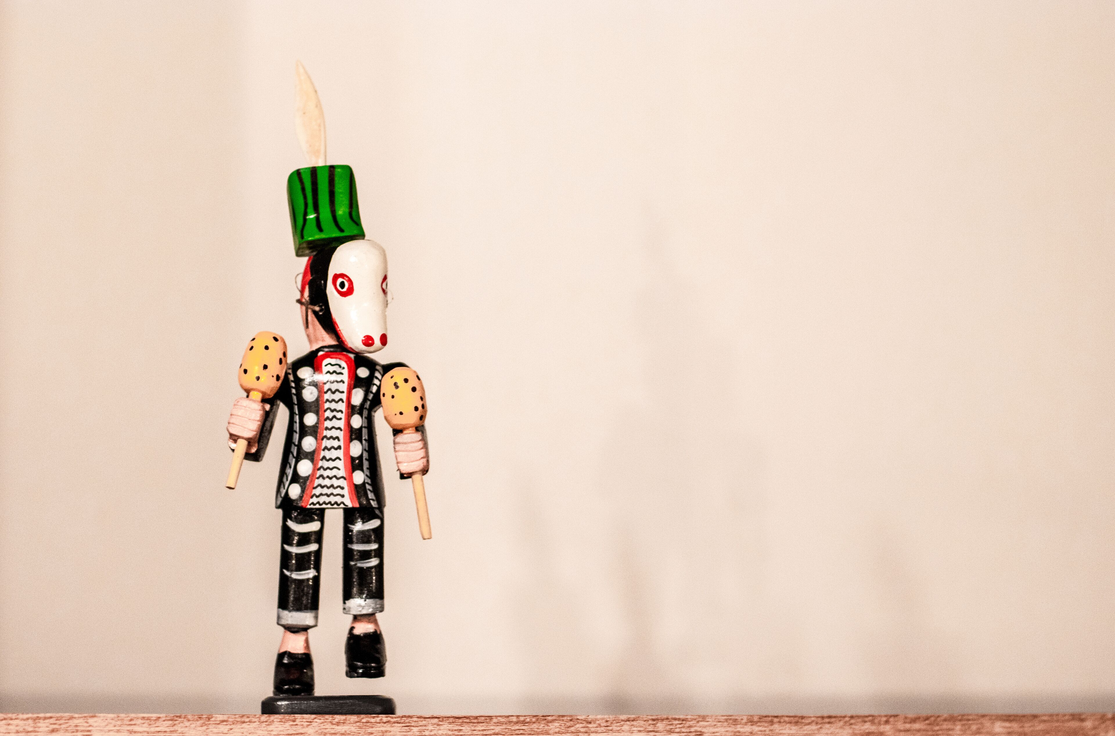 A wooden figure with a green hat and black and white striped pants.