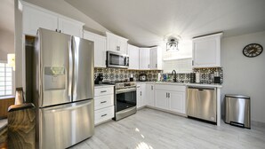 A modern kitchen with white cabinets, stainless steel appliances, and a patterned backsplash. - Romantic honeymoon cabin with hot tub! (Broken Bow)