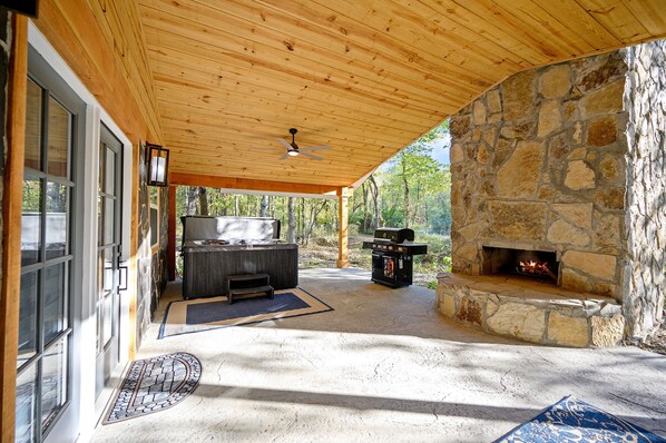 Un espace extérieur abrité, doté d’une cheminée en pierre, d’un barbecue et d’un coin salon.