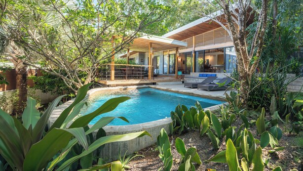 A modern house with a swimming pool surrounded by lush greenery. - Tropical Modern Home w/pool near the beach & surf (Nosara)