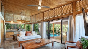 A spacious living area with a wooden ceiling, large windows, a pool, and a kitchen area. - Tropical Modern Home w/pool near the beach & surf (Nosara)