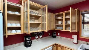 A kitchen with wooden cabinets, a coffee maker, and a dishwasher. - 3- Bedroom cottage near Pleasant Lake in Cadillac (Cadillac)