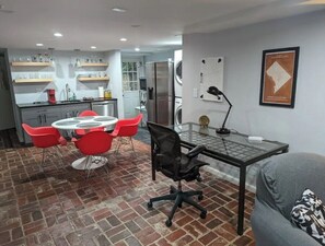 Cozy living space with a kitchen, dining area, and office nook, featuring a sofa and a round dining table.