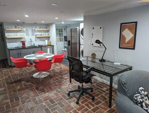 Cozy living space with a kitchen, dining area, and office nook, featuring a sofa and a round dining table.