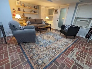 Relax in this inviting living room with a brick floor, patterned rug, and comfortable seating area featuring a sofa and armchairs.
