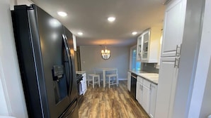 A kitchen with a black refrigerator, white cabinets, and a wooden floor. - 3 - Bedroom Cottage Near Lake Mitchell in Cadillac (Cadillac)