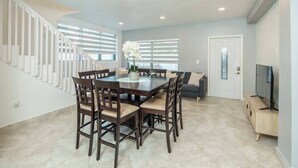 A modern interior with a dining area, staircase, and a television.