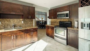 A modern kitchen with granite countertops, stainless steel appliances, and dark wooden cabinets.