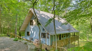 Une cabane avec un toit en pente, une terrasse en bois et un escalier menant à un porche abrité.