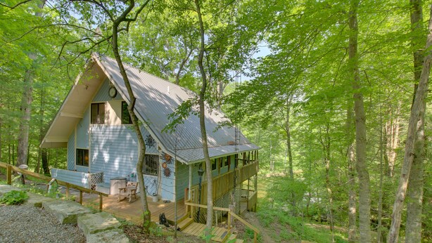 Une cabane dotée d’une terrasse en bois, d’un escalier et d’un porche.