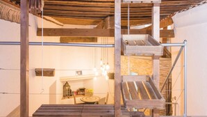 Eine Holztreppe mit Metallgeländer, die zu einem Raum mit Kamin und einem Tisch mit Blumen führt.