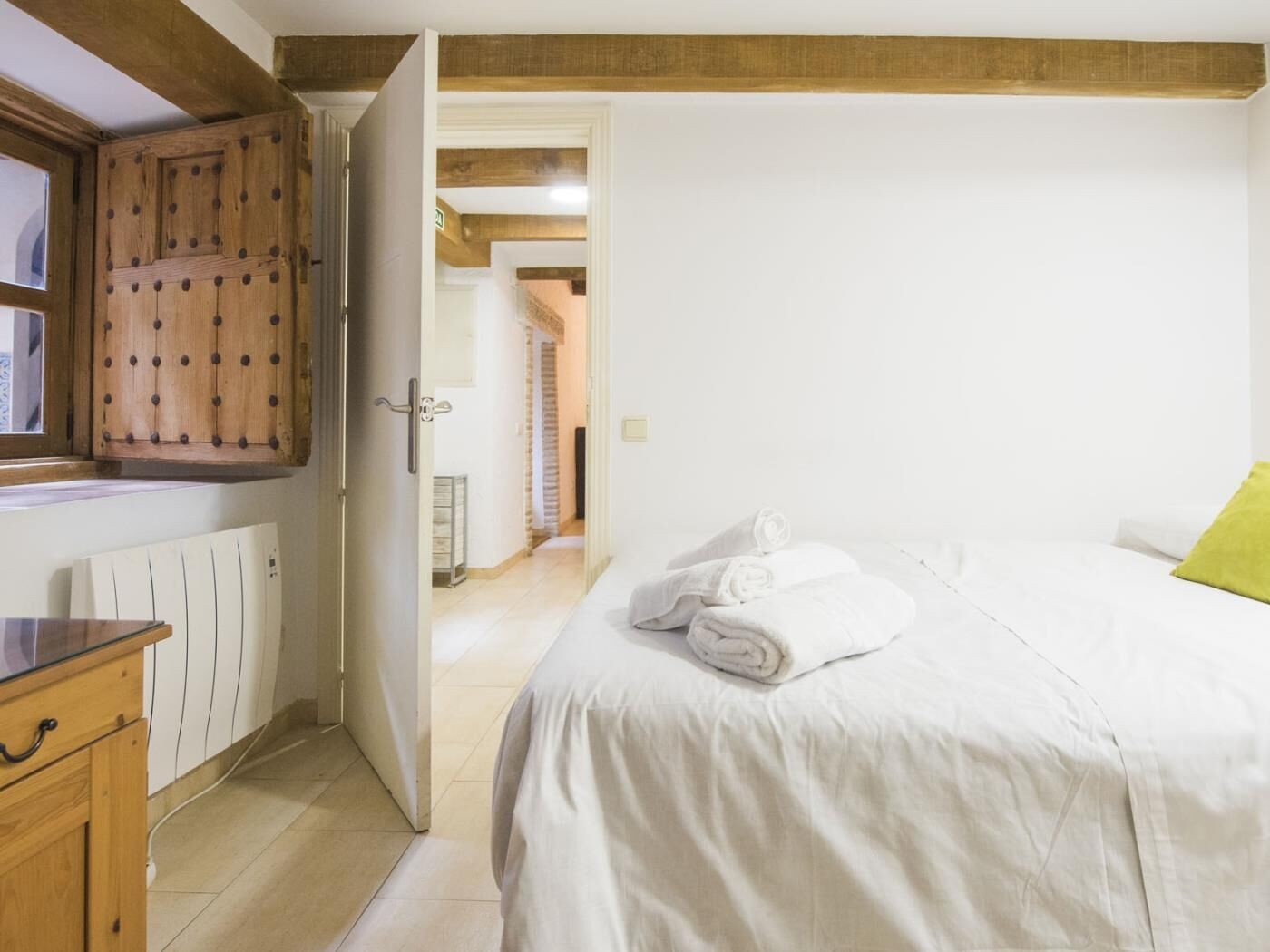 Un dormitorio con cama, armario de madera y radiador.