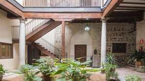Ein Innenhof mit einer Steinsäule, einer Holztreppe und Kübelpflanzen.