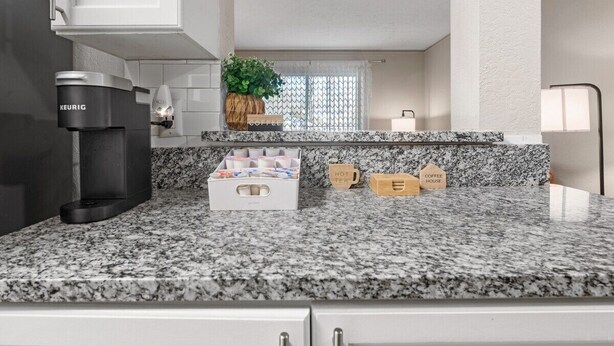 Una cocina con una cafetera Keurig, una zona de café con tazas y una planta.