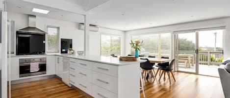A modern kitchen with white cabinetry, a central island, and a dining area with a view.