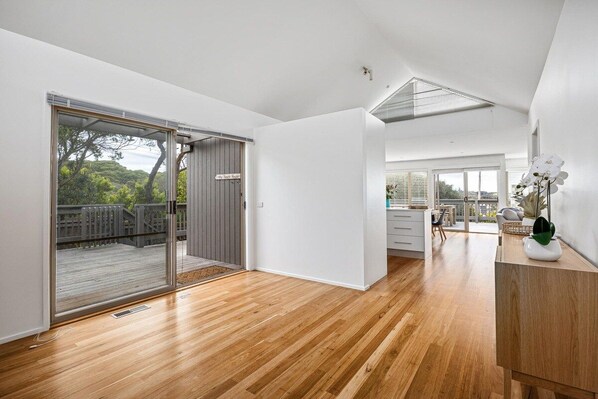 A spacious room with a wooden floor, a sliding glass door leading to an outdoor deck, and a view of the outdoors.