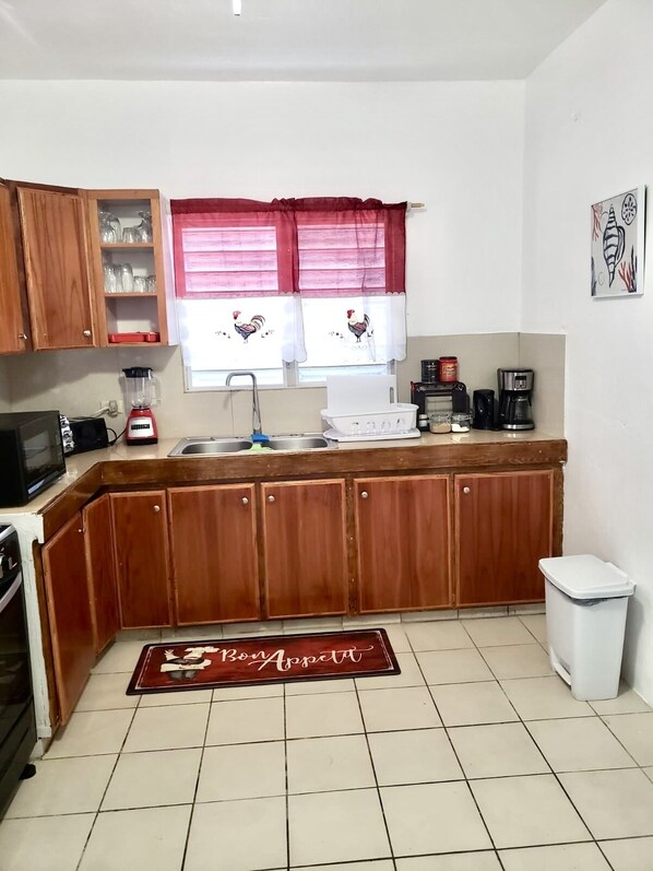 A compact kitchen with wooden cabinets, a sink, a microwave, and a coffee maker.