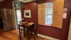 A dining area with a wooden table and chairs, a wooden door, and a window with wooden shutters. - Beautiful Cabin in quiet rural location (Sylvania)