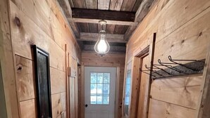 A wooden hallway with a polished floor, a white door, and a hanging light fixture. - Beautiful Cabin in quiet rural location (Sylvania)