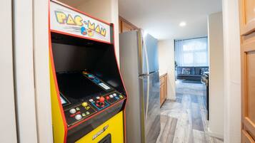 A Pac-Man arcade machine in a hallway with a kitchen area visible in the background.