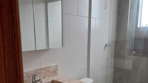 A bathroom with a marble sink, a toilet, and a glass shower enclosure. - Suite with beautiful sea view!! (Florianópolis)