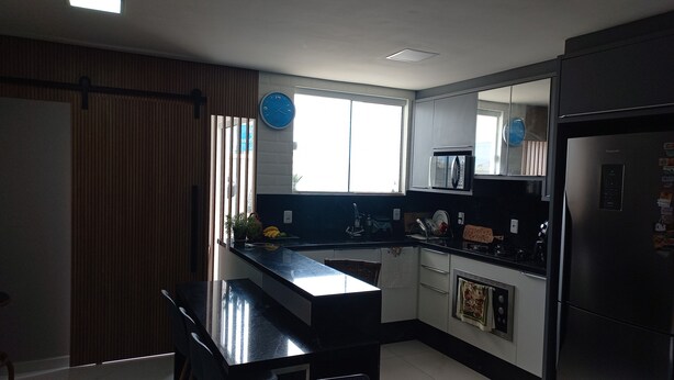 A modern kitchen with a black countertop, stainless steel appliances, and a window providing natural light. - Suite with beautiful sea view!! (Florianópolis)