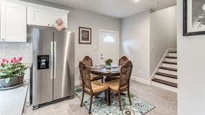 Une cuisine moderne avec un réfrigérateur en acier inoxydable, une table à manger en bois et des chaises, ainsi qu’un escalier menant à un autre niveau.