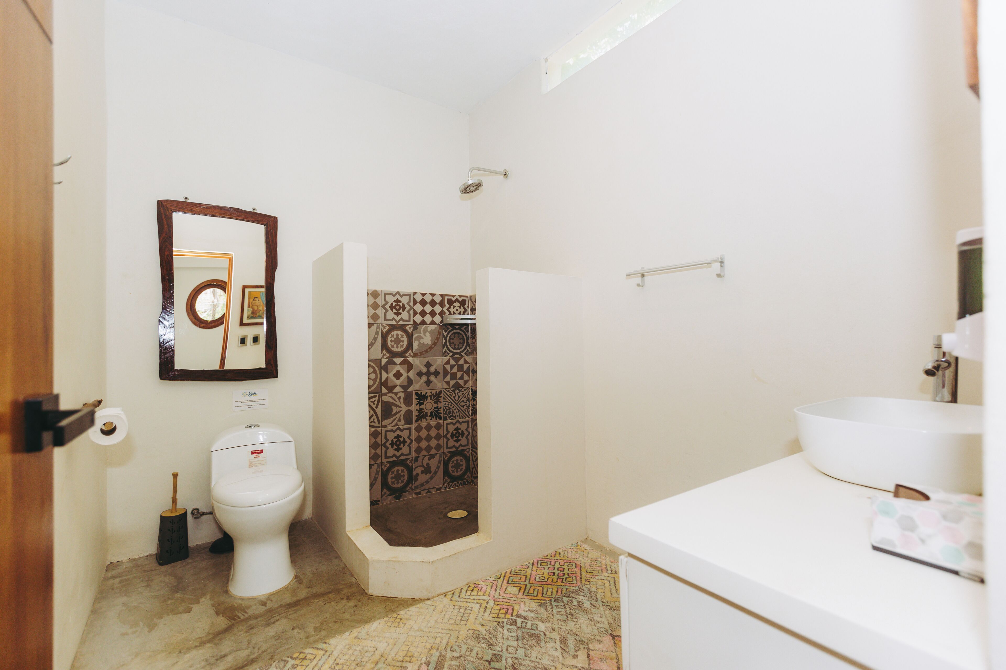 Une salle de bain équipée de toilettes, d’une douche, d’un lavabo et de carreaux décoratifs.