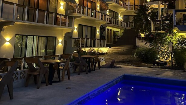 Un complexe hôtelier doté de villas aux toits de chaume, d’une piscine et d’un espace de détente en plein air.