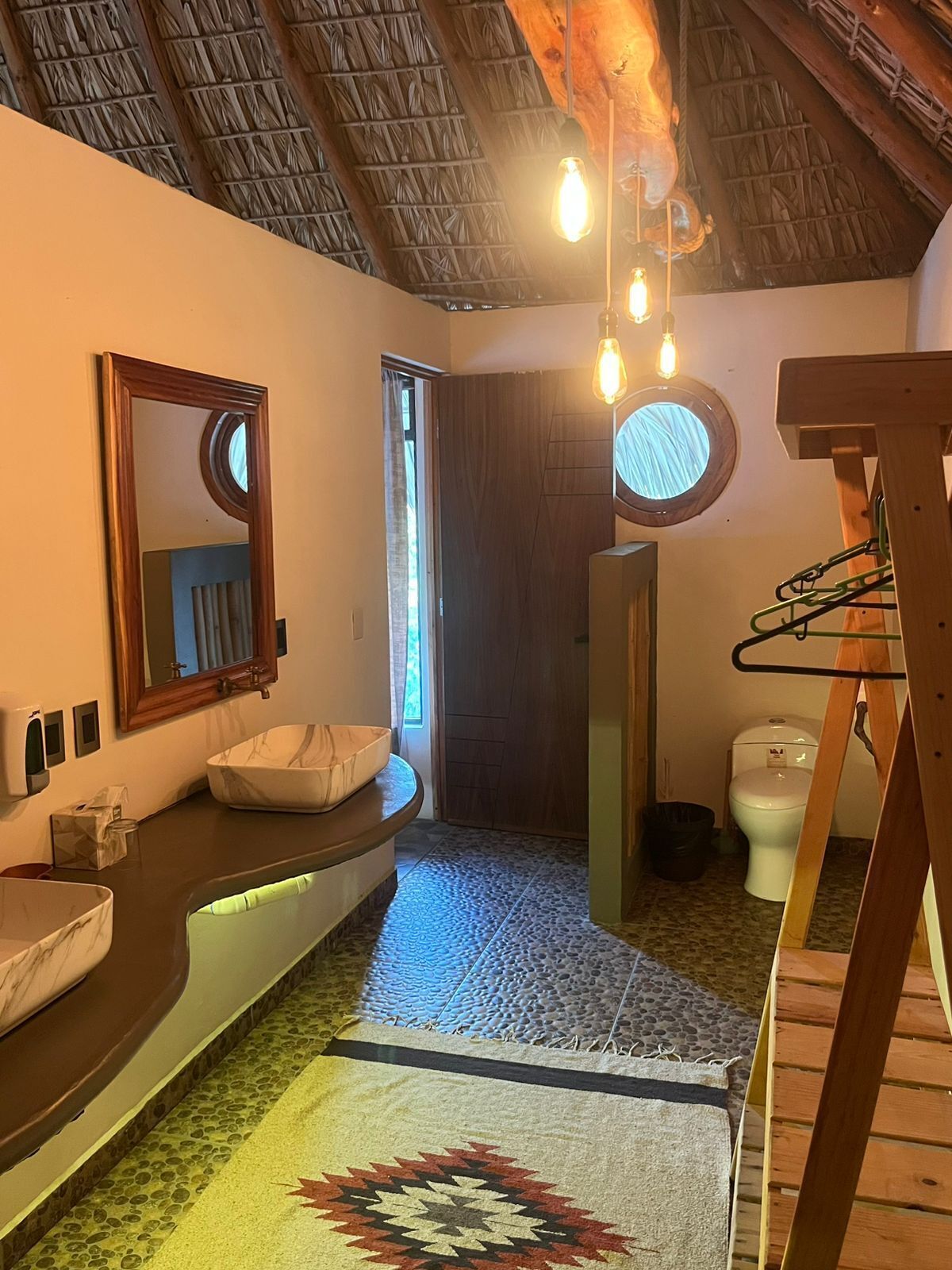 A bathroom with a curved vanity, a large mirror, a sink, and a toilet.