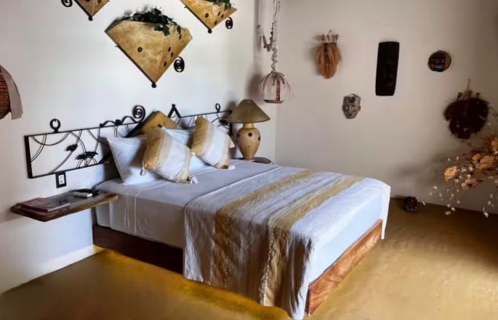 A bedroom with a bed, bedside table, and wall decorations.