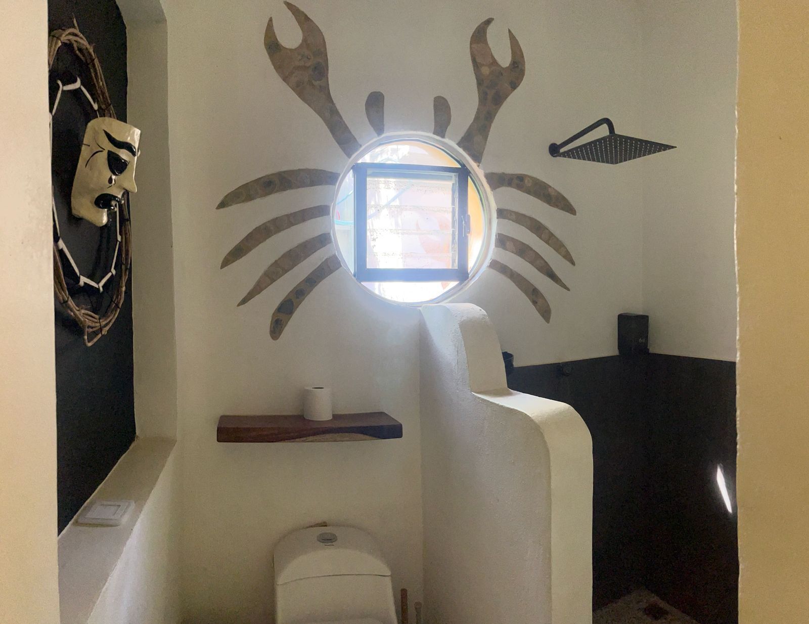 A bathroom with a round window, a towel rack, and a toilet.