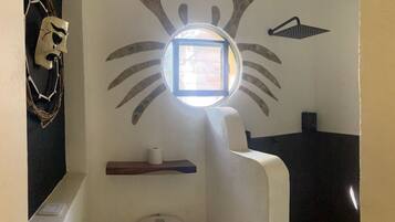 A bathroom with a round window, a towel rack, and a toilet.