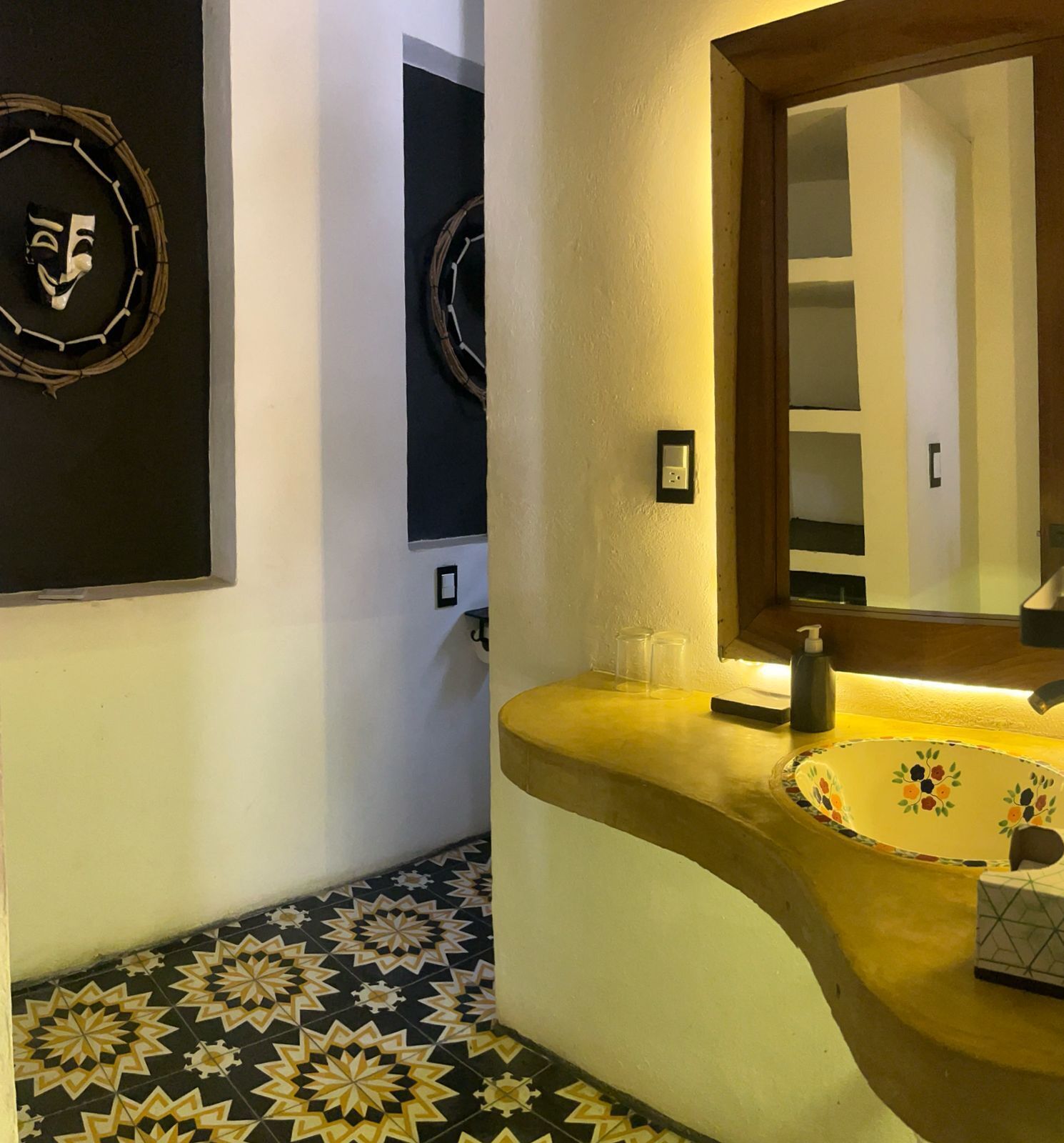 A bathroom with a curved sink, a mirror, and a patterned floor.